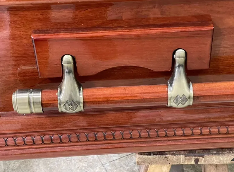 Close view of metal coffin handles fitted to a polished wooden casket
